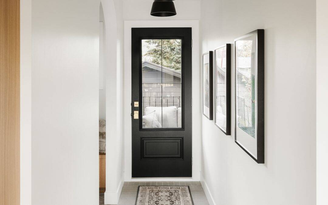Bright and welcoming home entryway with black door and framed artwork.