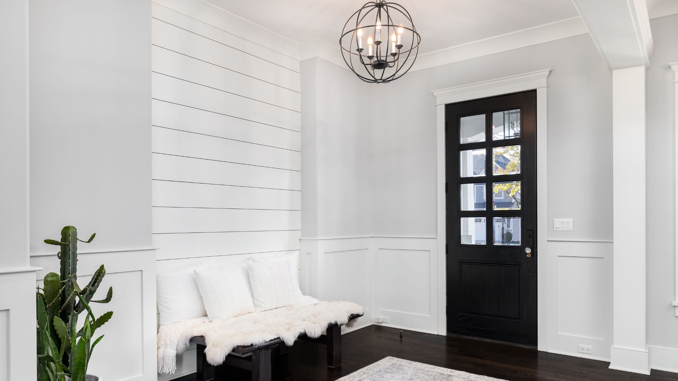 Bright modern interior with white walls, black door, and cozy seating area.