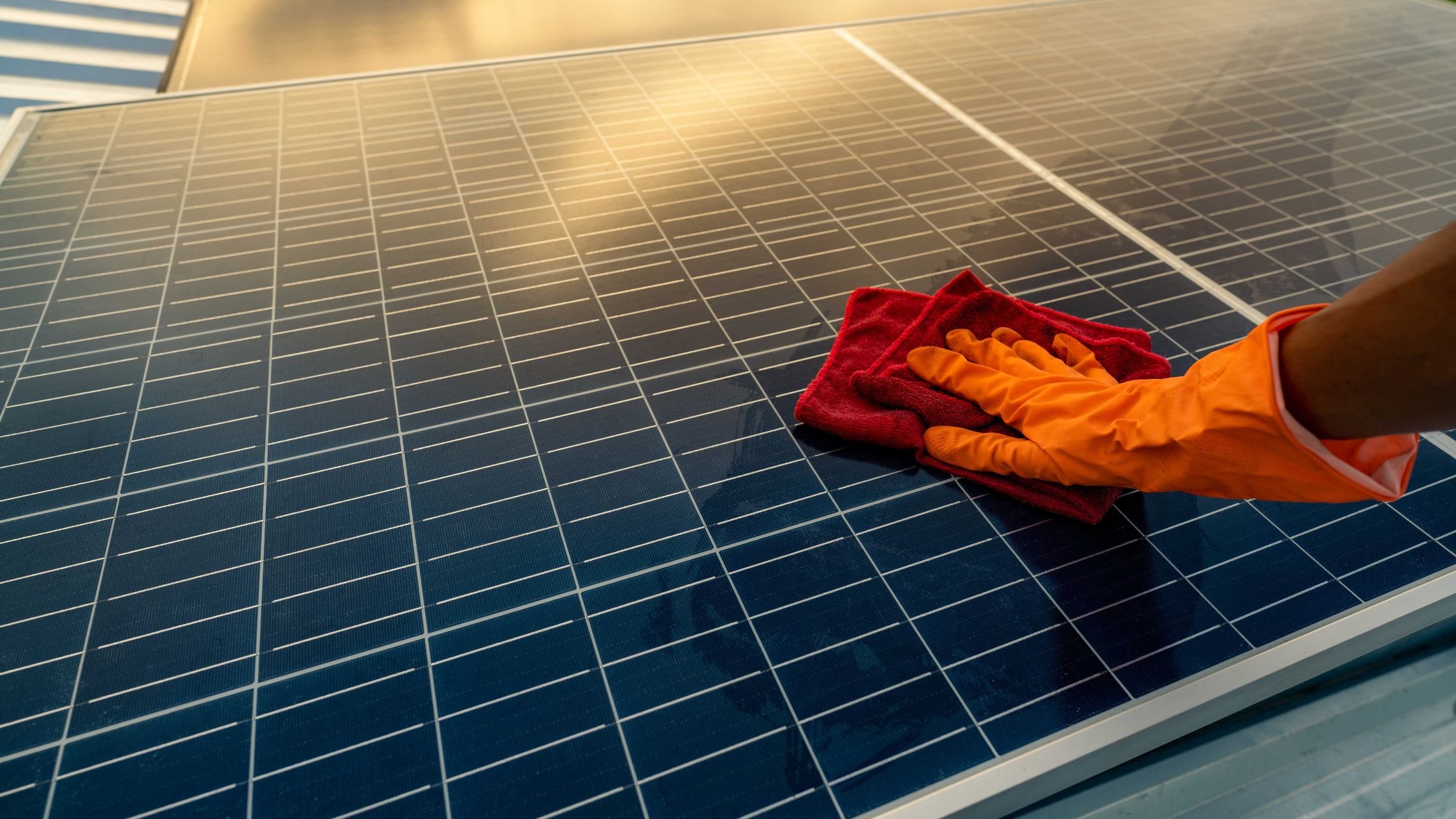 Cleaning solar panels with a red cloth for optimal energy efficiency.