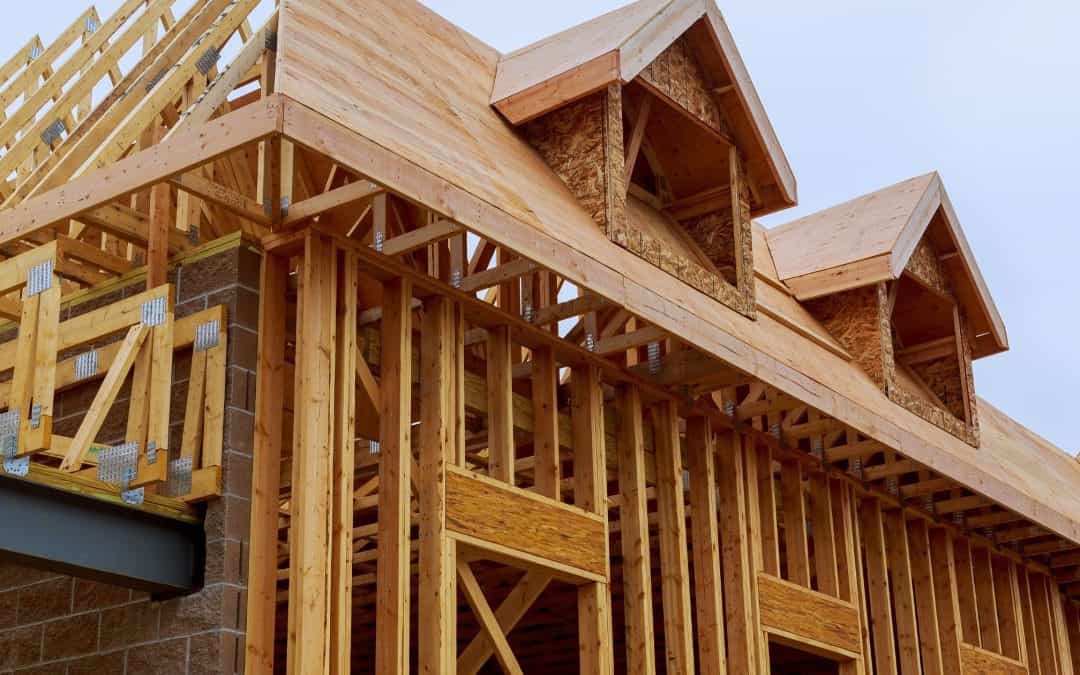 New wooden house frame being built with detailed roof structures and framing.