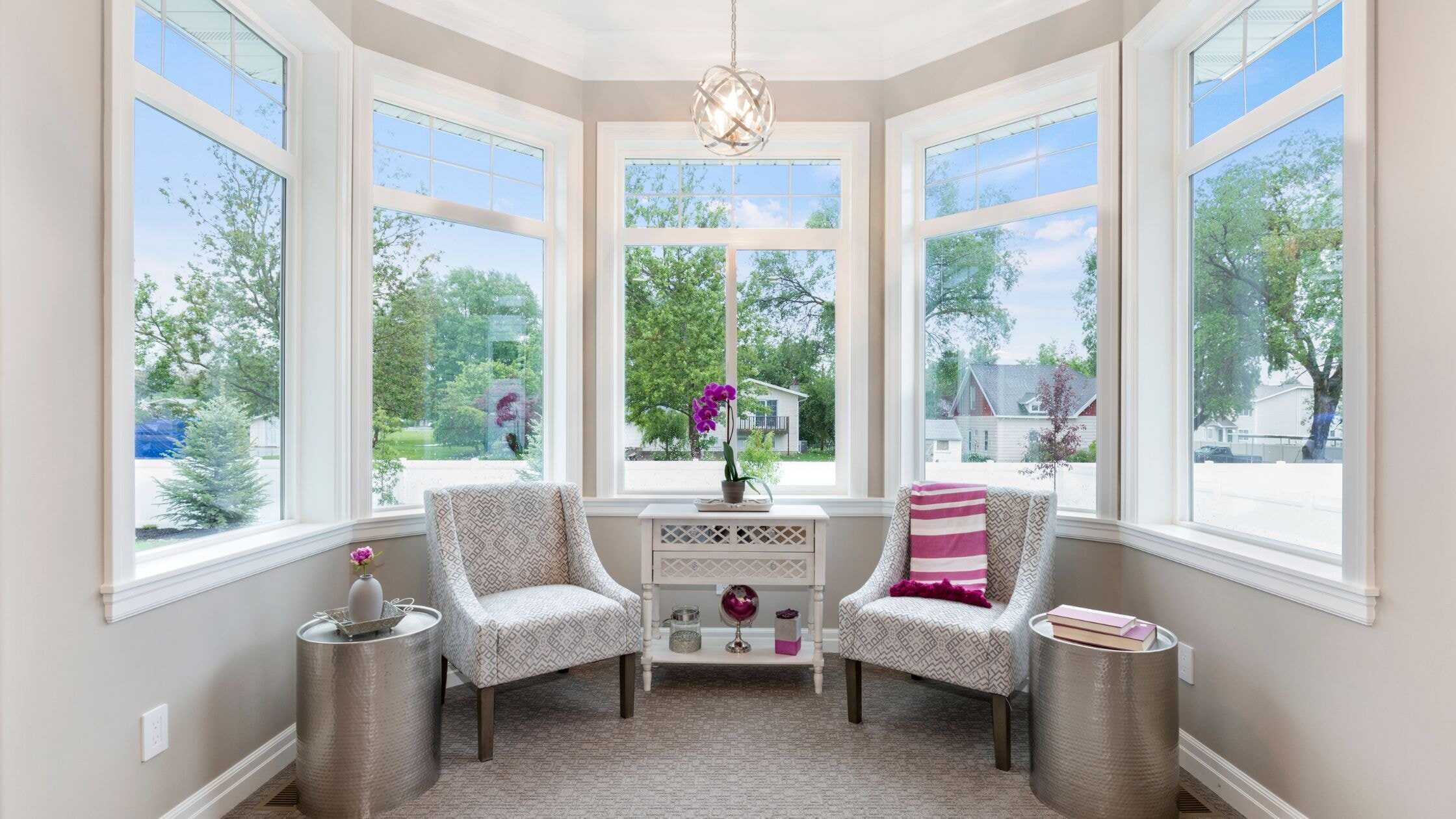 Bright sunroom with large windows, comfortable chairs, and decorative accents for relaxing and enjoy.
