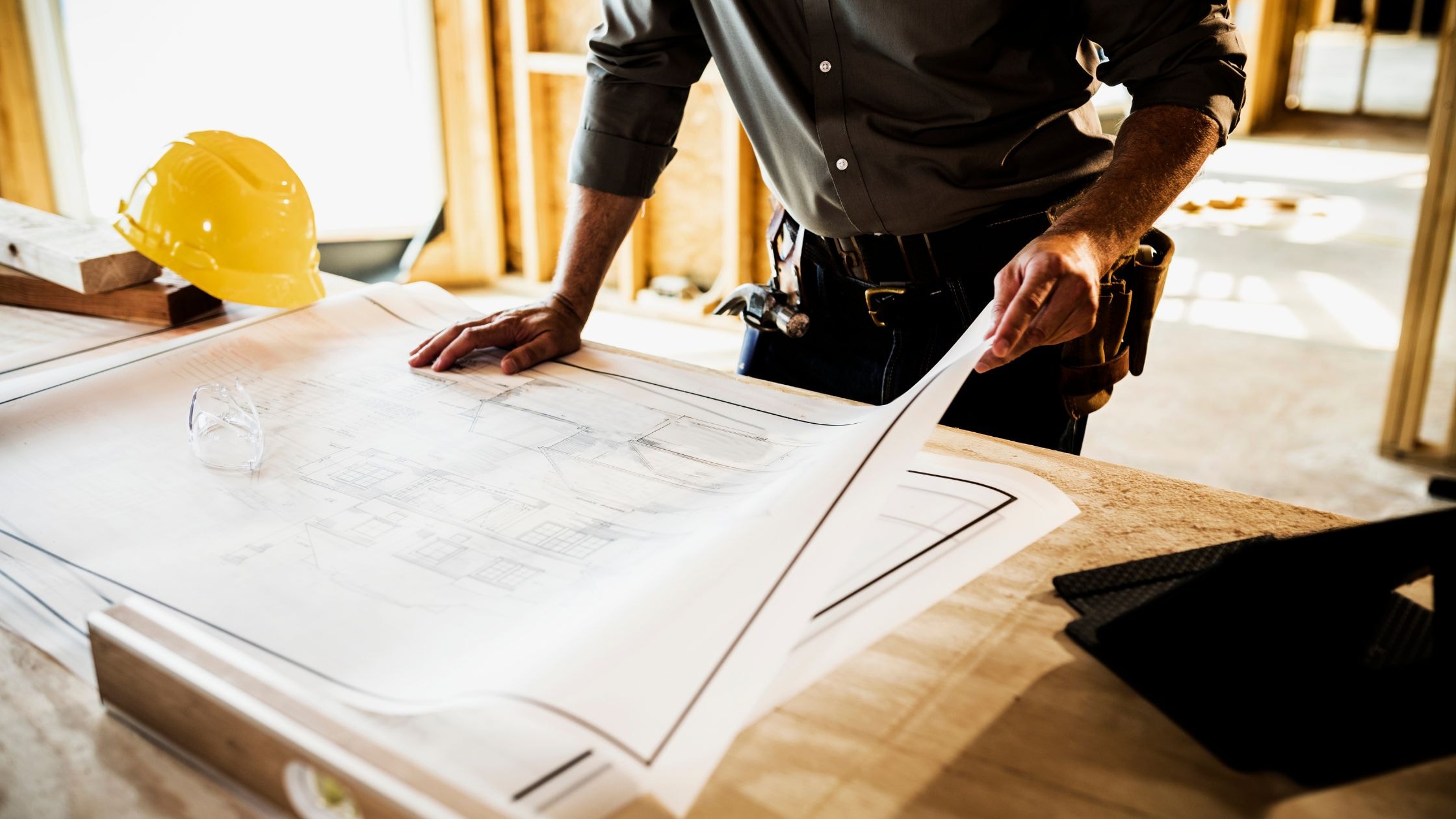 Architect reviewing construction plans at a building site.