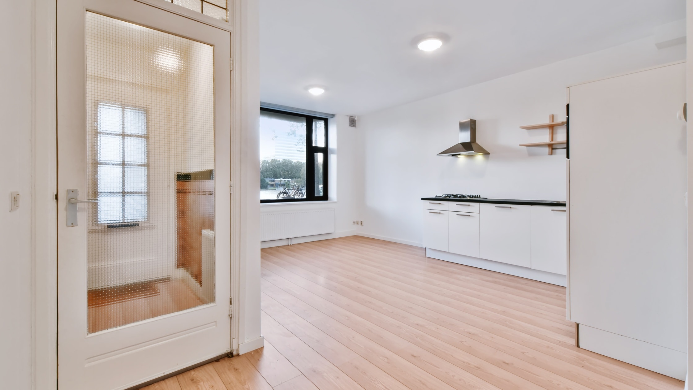 Modern kitchen with white cabinets, black countertops, and stainless steel appliances. Bright, open.