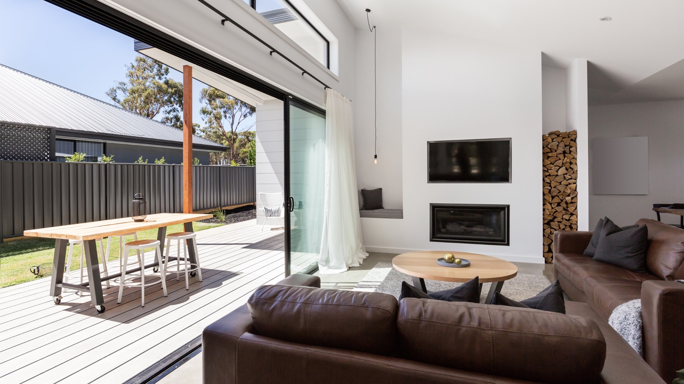 Bright modern living room with large glass doors, fireplace, and cozy seating area.