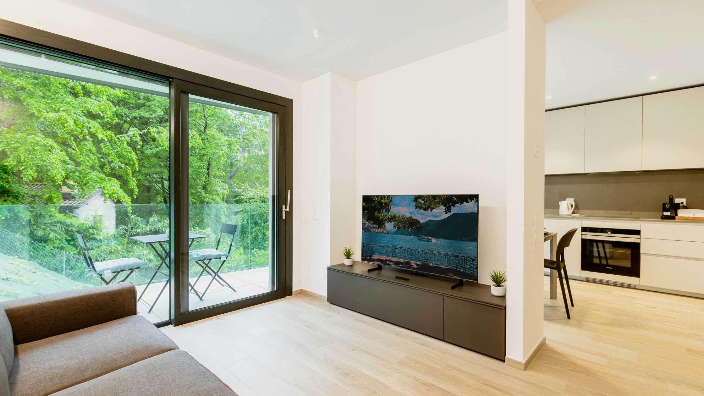 Bright living room with large glass sliding doors opening to a lush green outdoor space.
