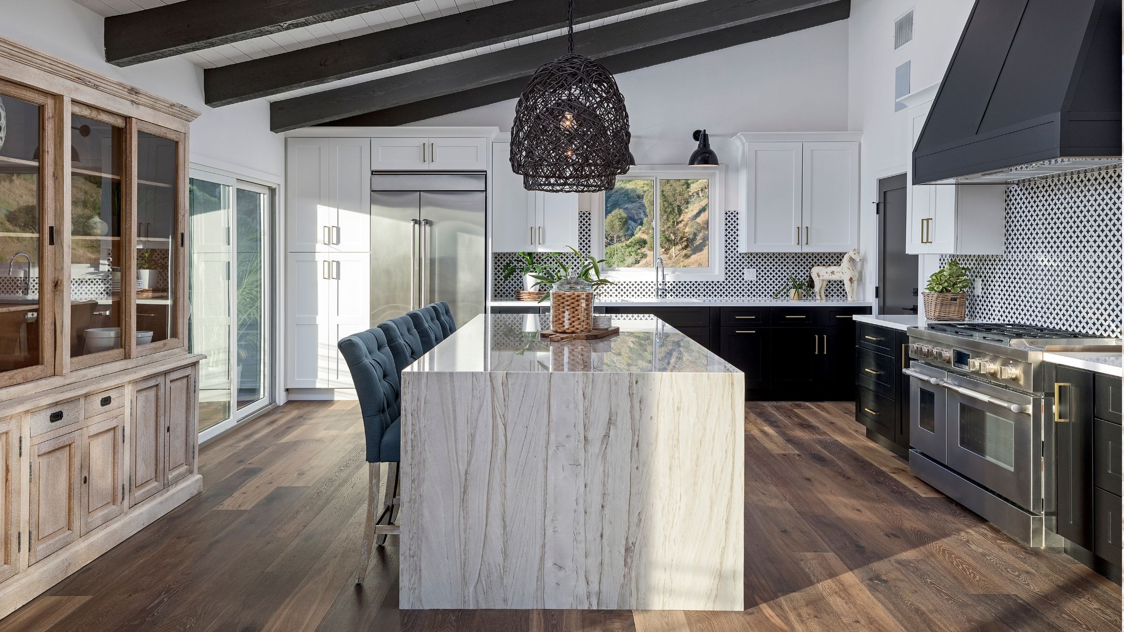 Spacious modern kitchen with black and white cabinetry, marble island, and stylish lighting fixtures.