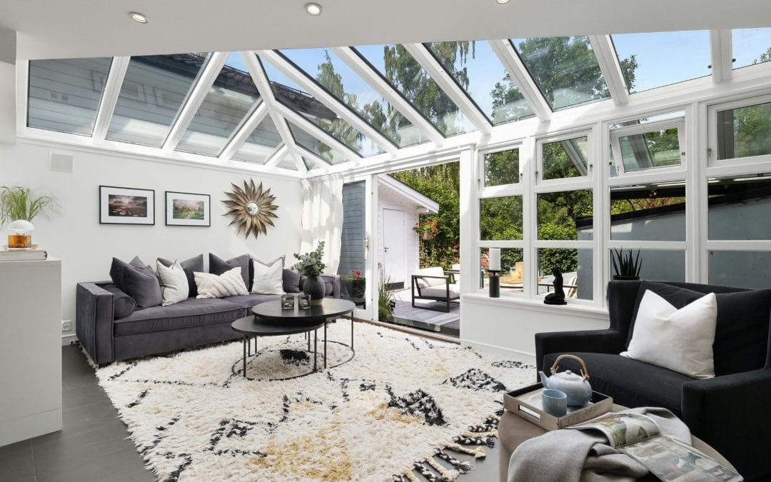 Bright sunroom with glass ceiling and cozy seating area, perfect for relaxing and enjoying sunlight.