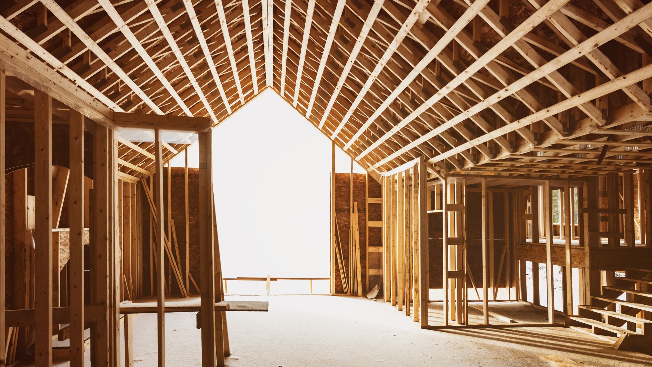 Interior framing of a new residential home under construction showing wooden studs and roof trusses.