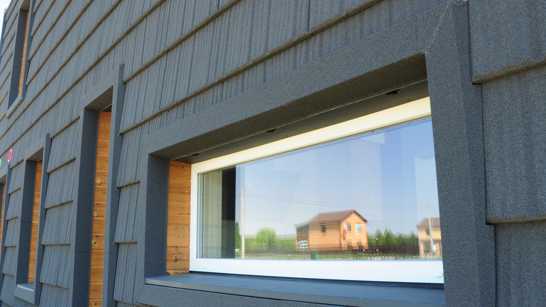 Modern industrial building with blue siding and large window, showcasing construction quality.