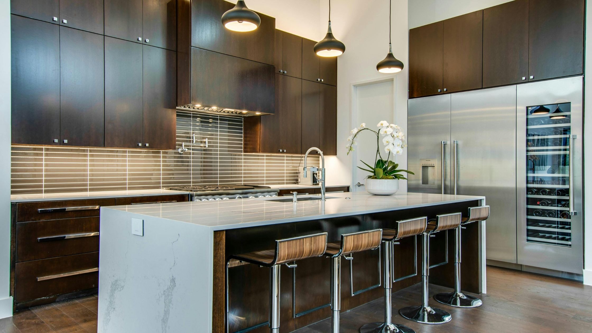 Contemporary kitchen with dark wood cabinets, white island, and stainless steel appliances.