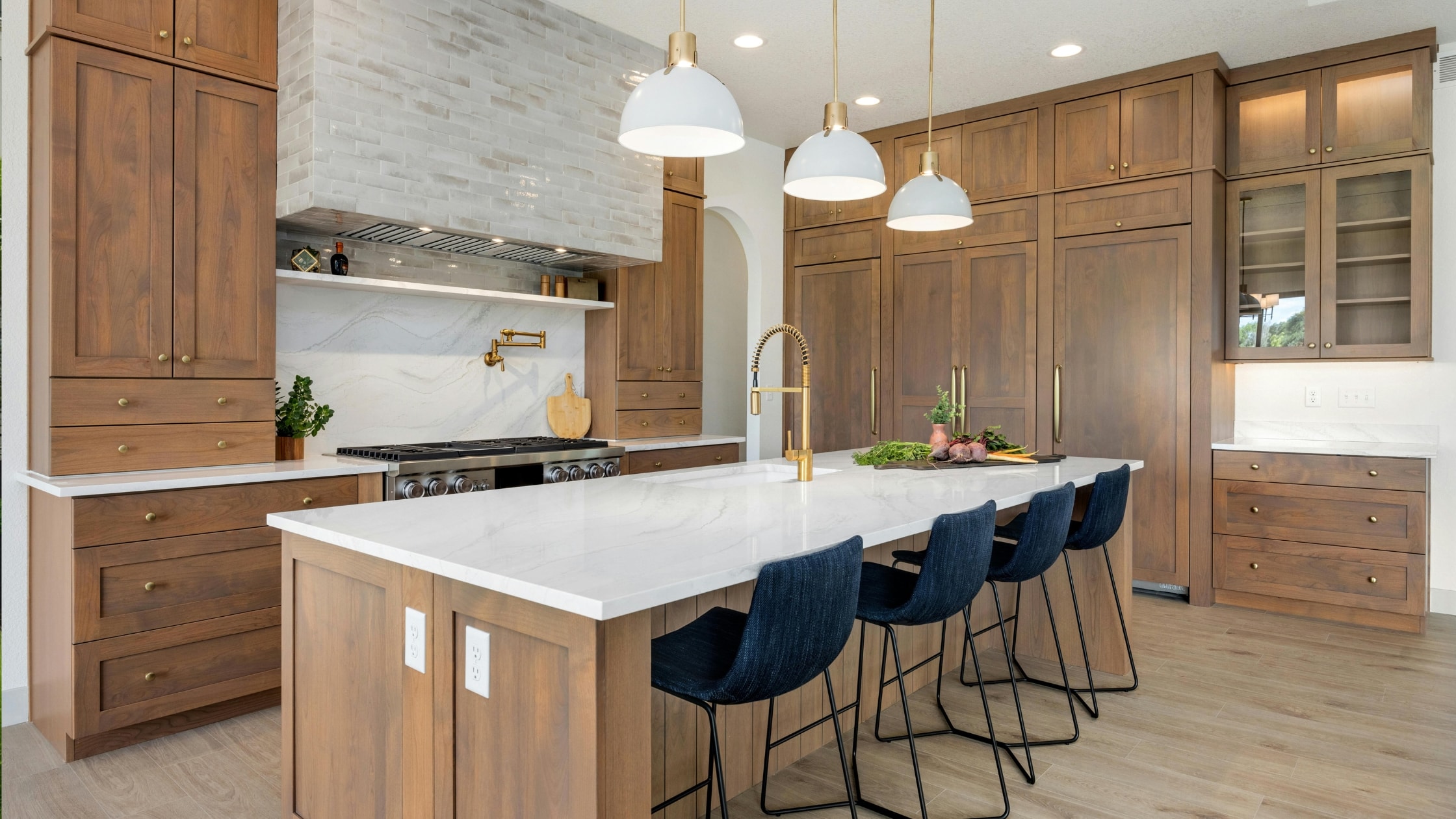 Contemporary kitchen featuring wooden cabinetry, a white island, and modern lighting fixtures.