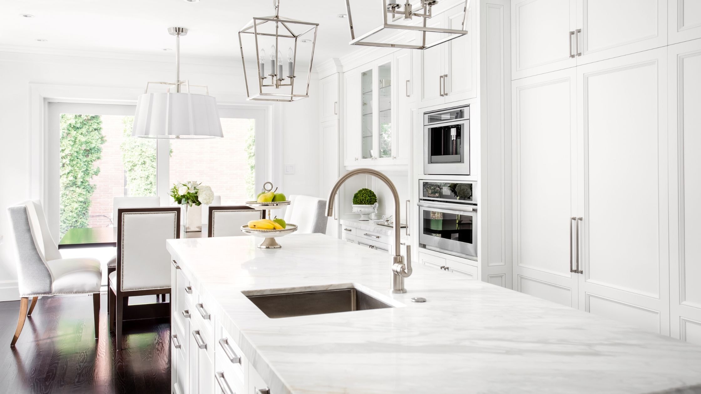 Bright modern white kitchen with marble countertops and ample storage cabinets.
