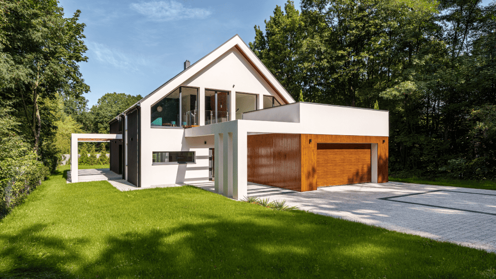 Contemporary house with white and wood accents, surrounded by lush greenery.