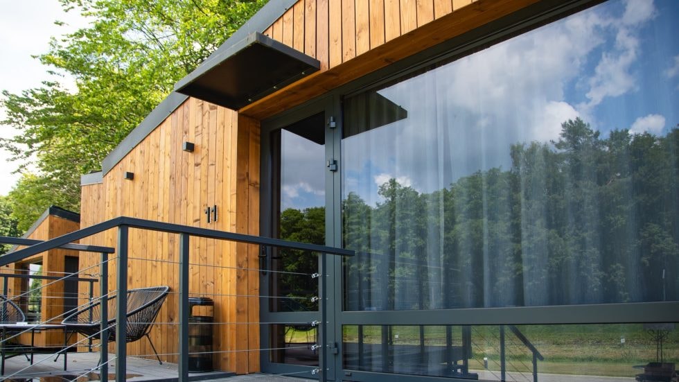 Contemporary wooden house with large glass windows and outdoor balcony.