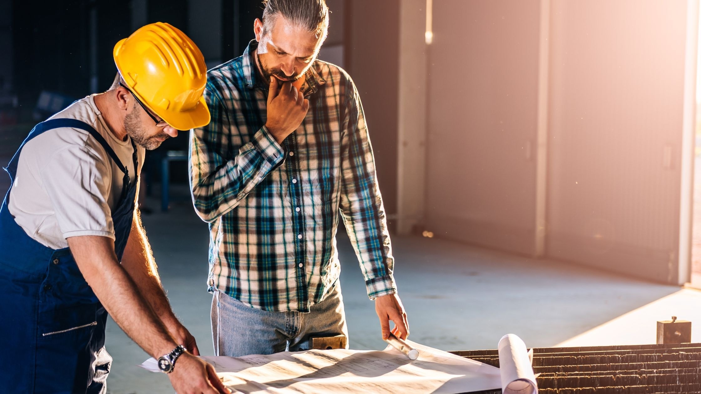 Construction workers reviewing blueprints at a building site.