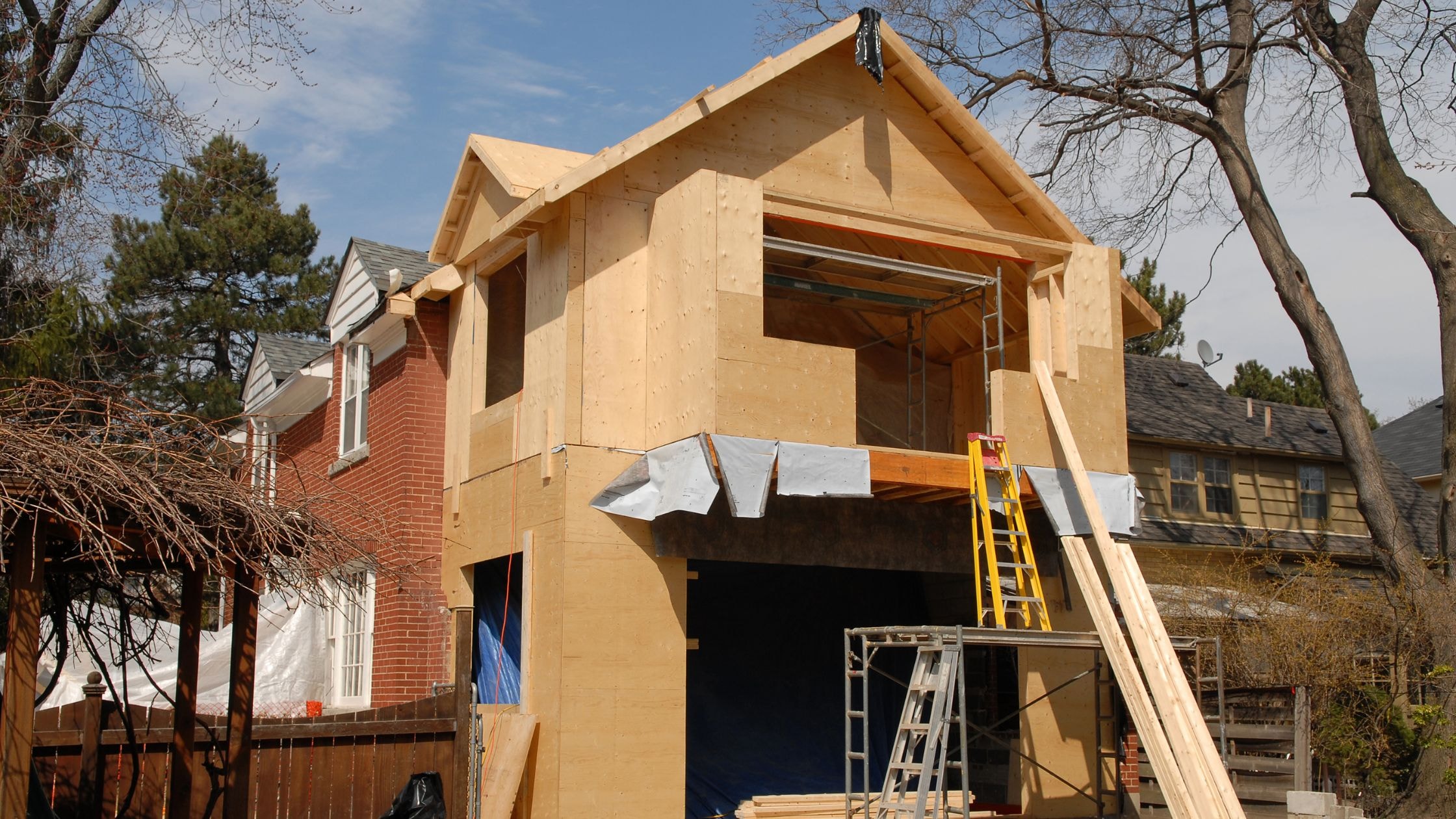 New residential home being built with wooden framing in a suburban neighborhood.