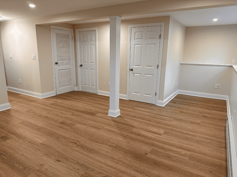 Modern basement with hardwood flooring, white doors, and neutral walls.