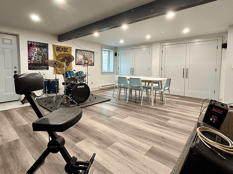 Spacious basement with music area, drum set, and workout equipment for family fun.