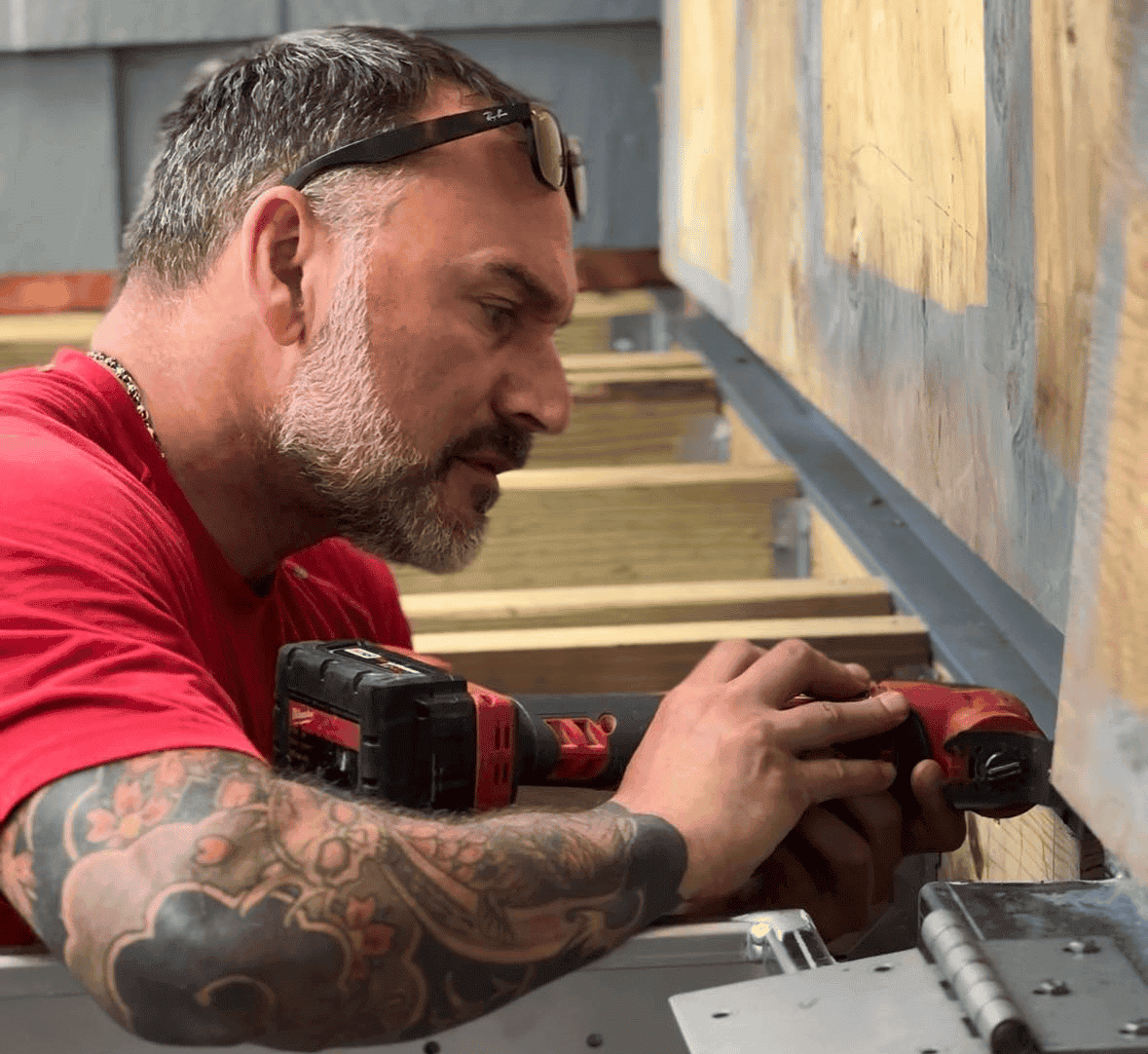 Construction worker installing or repairing a wooden structure with power tools.