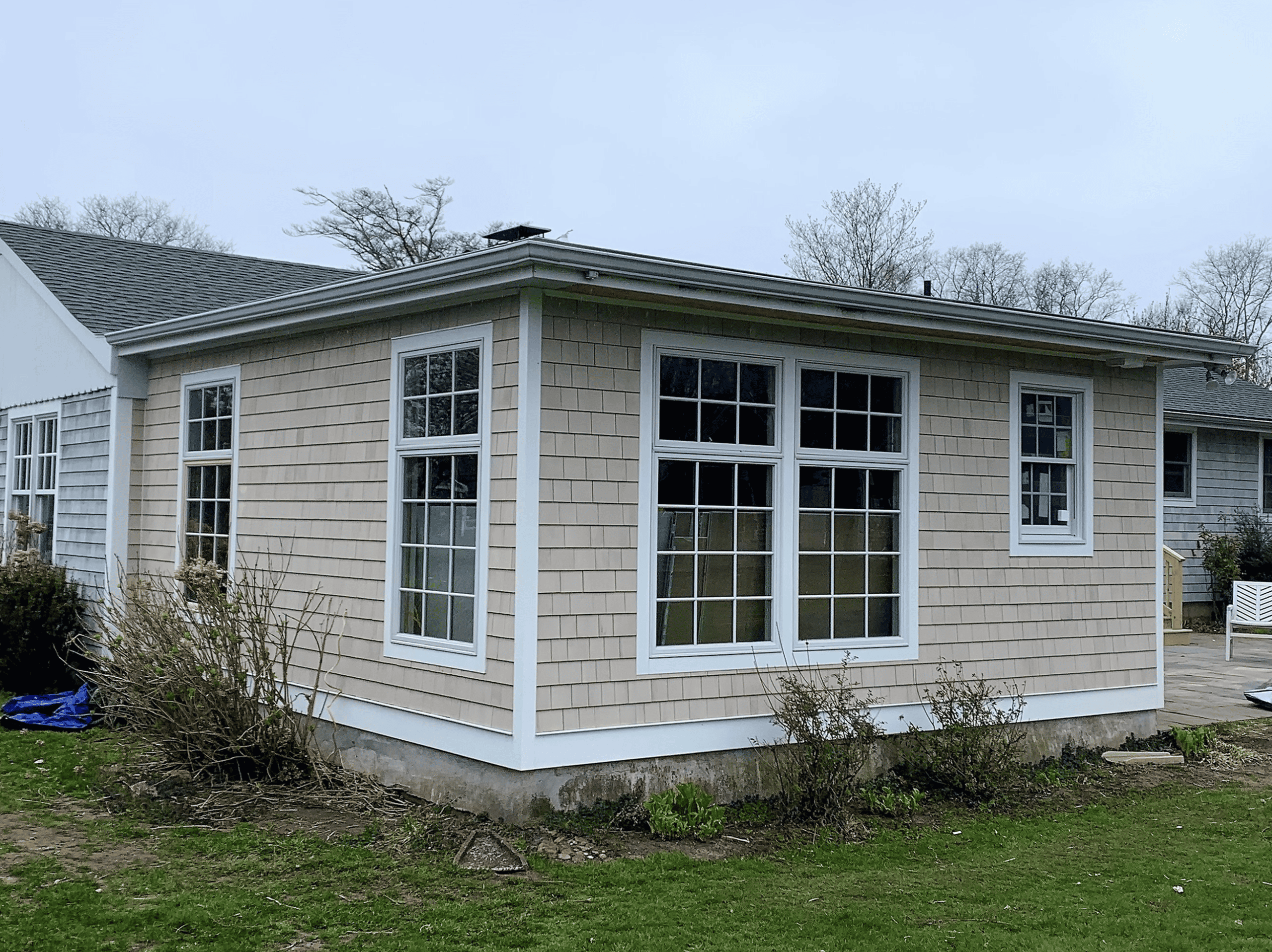 Beautiful new home addition with large windows and beige siding.