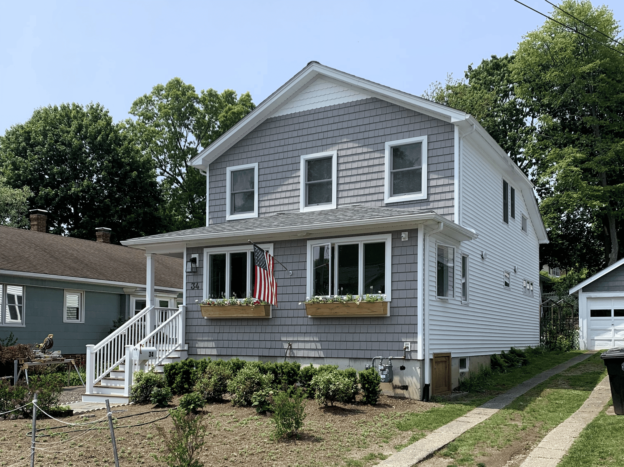House with gray siding and white trim, featuring a front porch with an American flag.