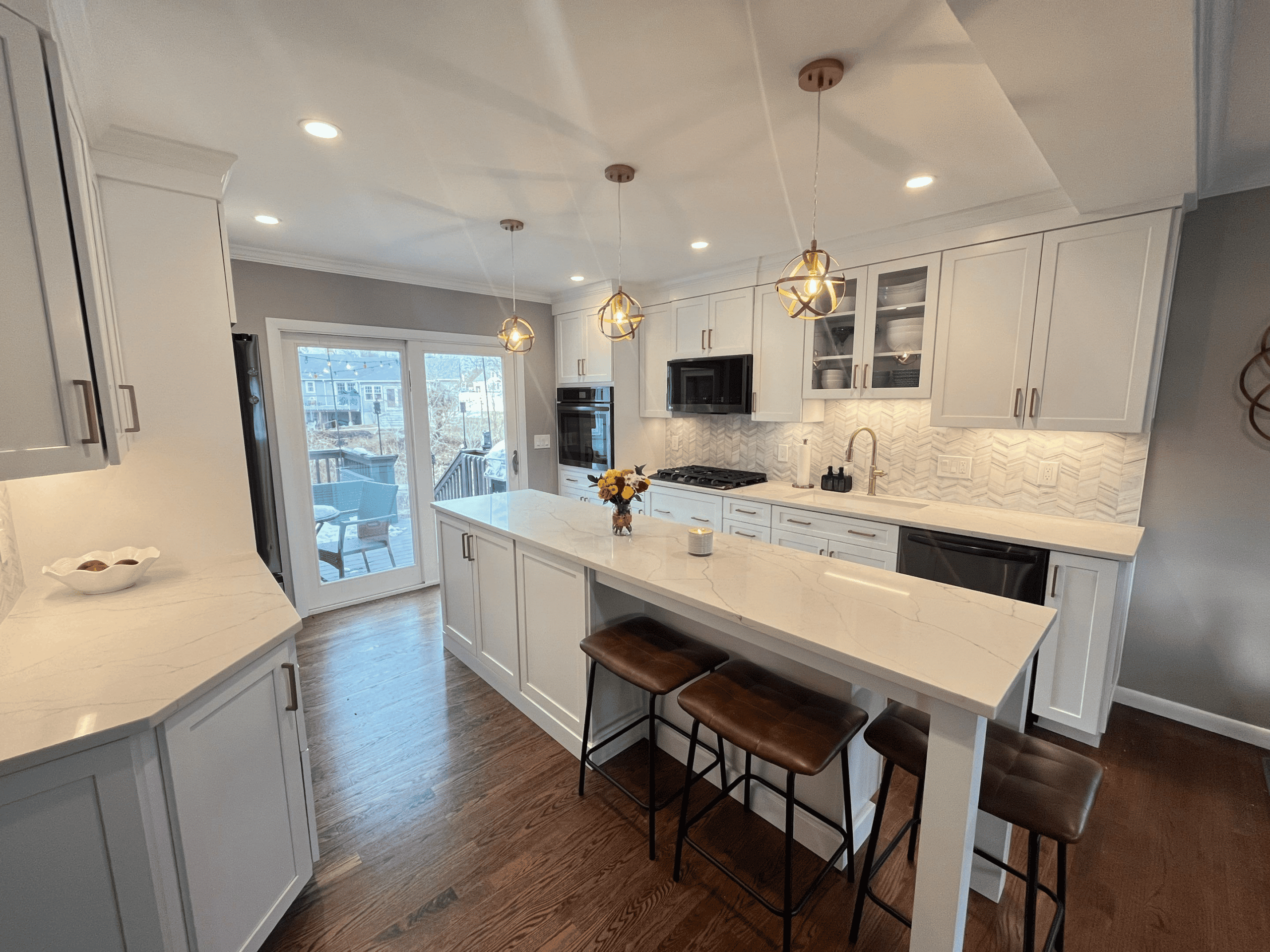 Bright, modern kitchen featuring a white island, pendant lighting, and ample natural light from slid.