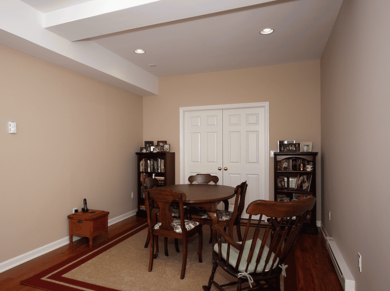 Elegant dining room with wooden table and chairs, beige walls, and built-in bookshelves.