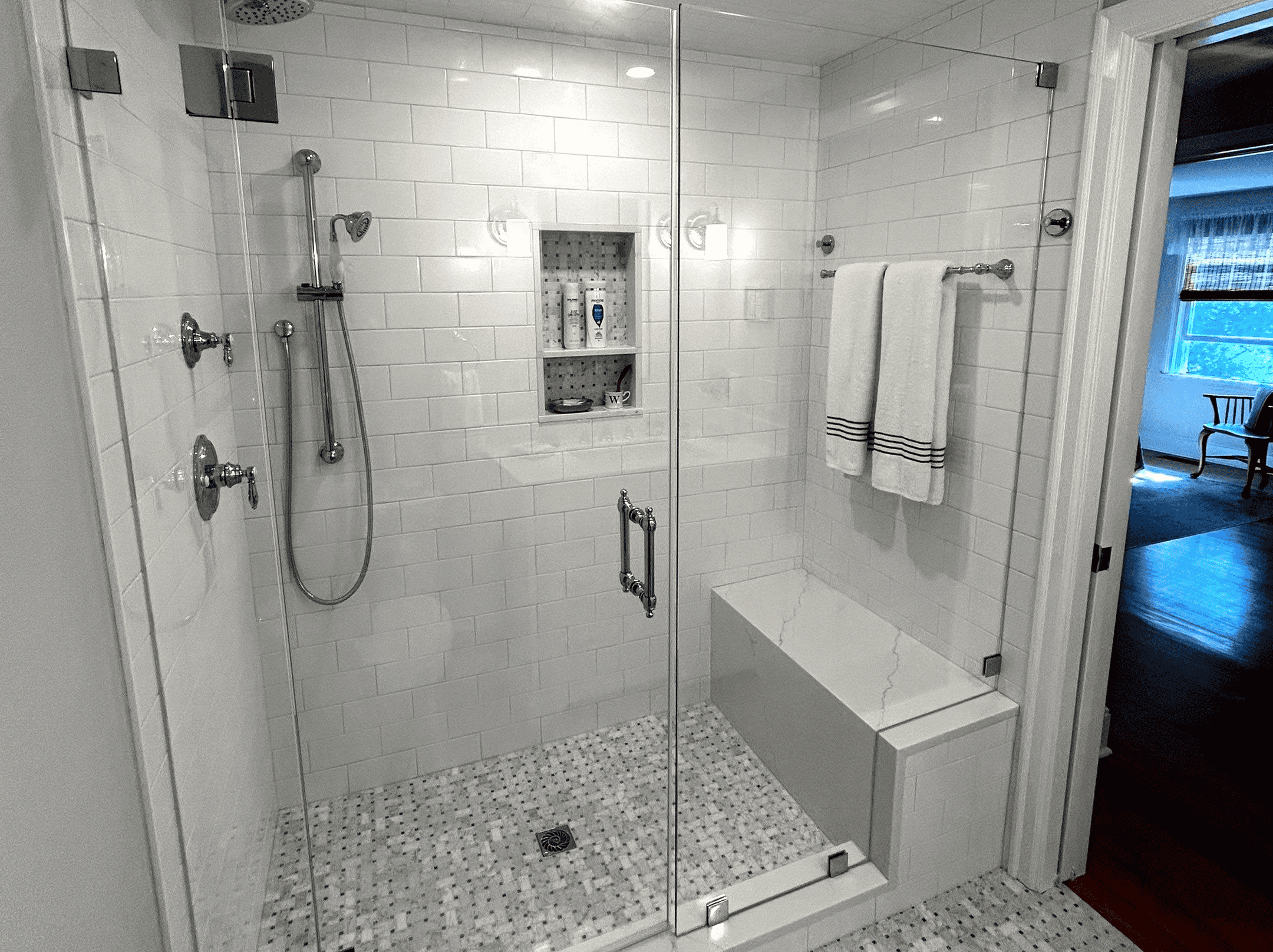 Stylish walk-in shower with glass enclosure, multiple shower heads, and built-in niche for toiletrie.