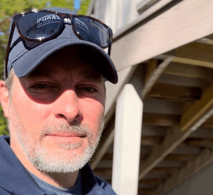 Skilled home builder inspecting outdoor construction site with wooden deck.