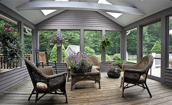 Sunroom with wicker furniture and lush greenery.