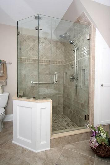 Glass shower enclosure with beige tile walls and pebble floor.