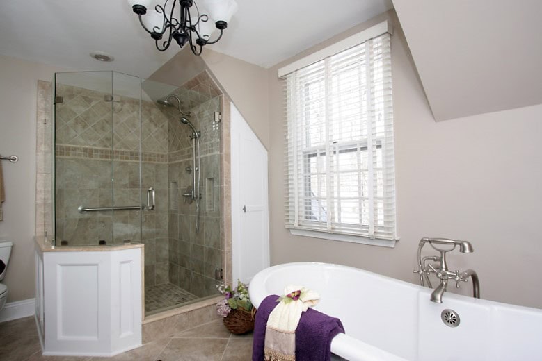 Bathroom with glass-enclosed shower and bathtub, featuring neutral tile and bright natural light.
