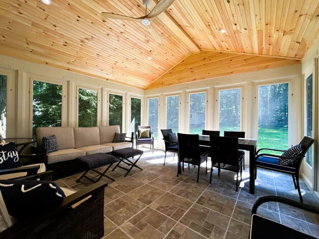Sunroom with large windows and wooden ceiling.