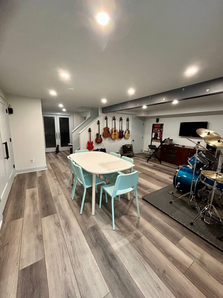 Modern music room with guitars, drum set, and cozy seating area.