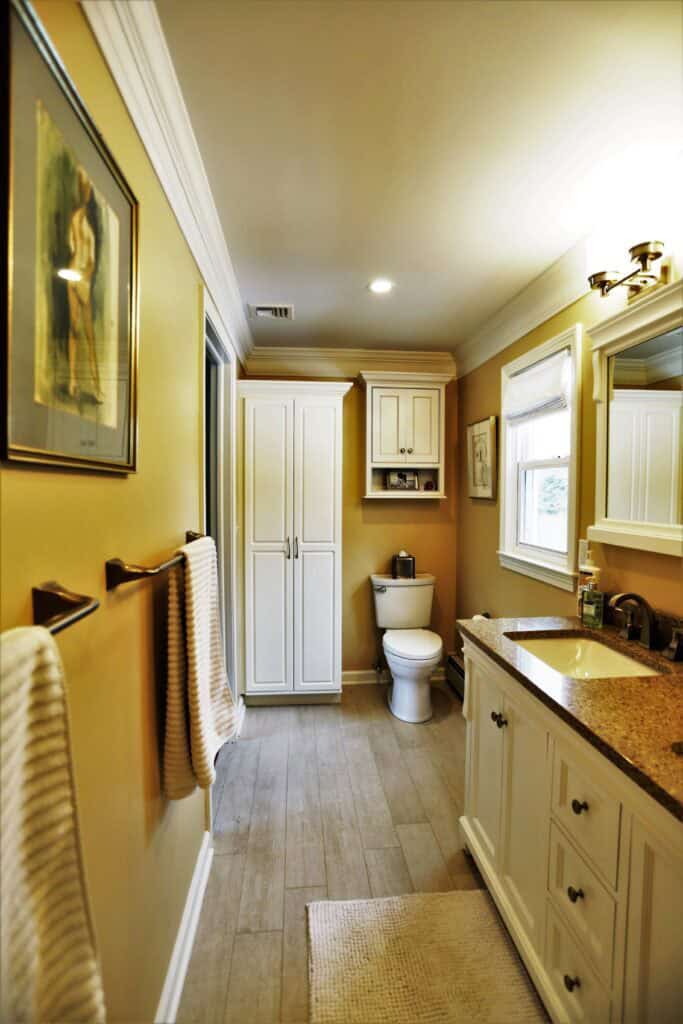 Modern bathroom with white cabinetry, beige walls, and natural light.