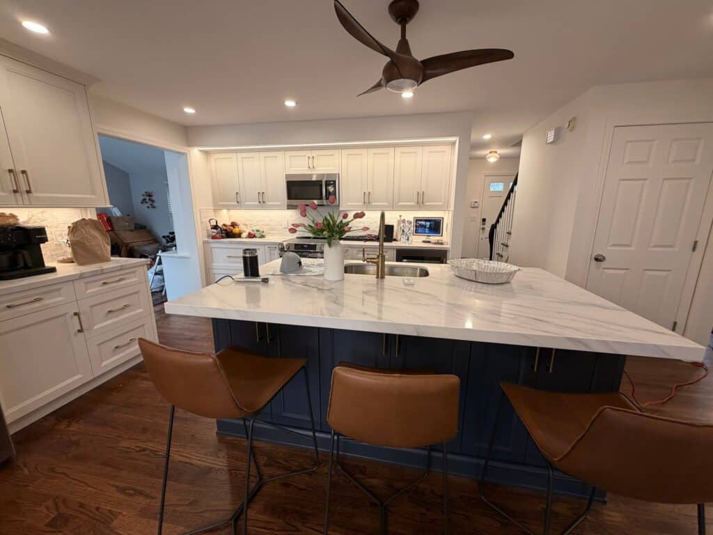 Kitchen with white cabinetry, marble island, and modern appliances.