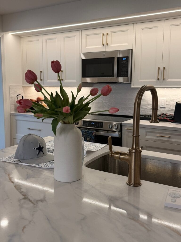 Modern kitchen featuring white cabinetry, stainless steel appliances, and a marble countertop with a.