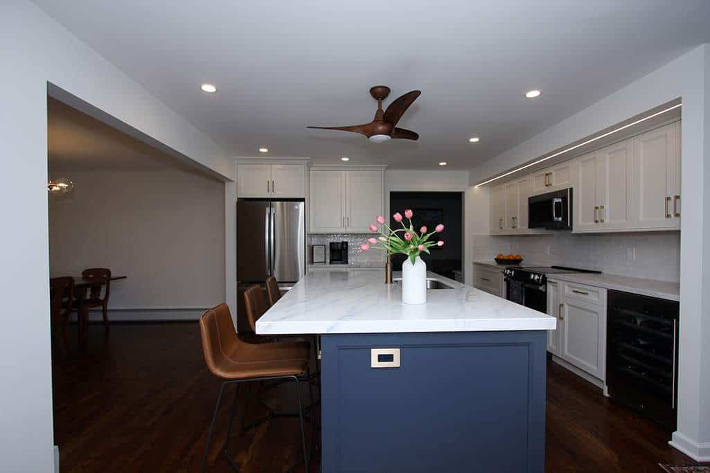 Spacious modern kitchen with white cabinetry, a central island with a blue base, and stainless steel.