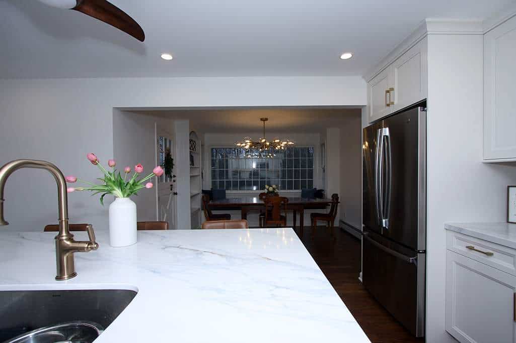 Modern kitchen with white cabinetry and marble countertops, featuring stainless steel appliances and.