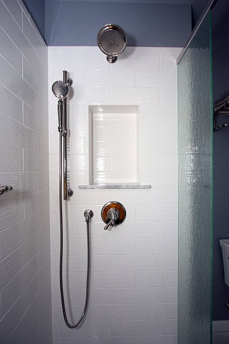 Contemporary shower with dual showerheads and sleek white tile walls.