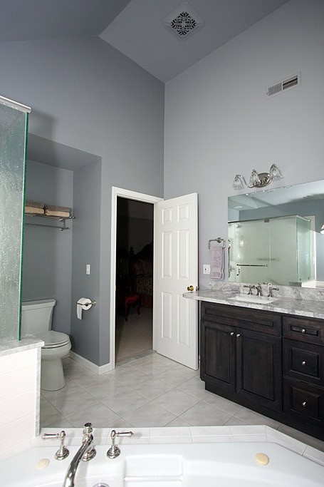 Modern bathroom with dark wood vanity, large mirror, and light gray walls.