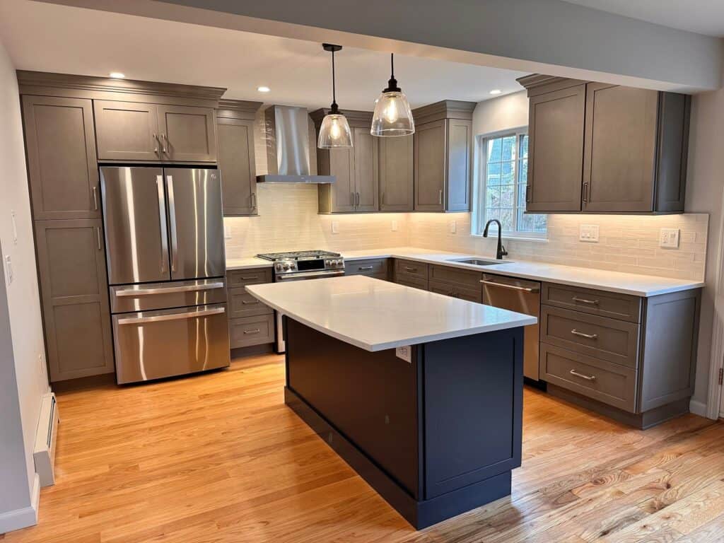 Modern kitchen with gray cabinets, stainless steel appliances, and a central island.