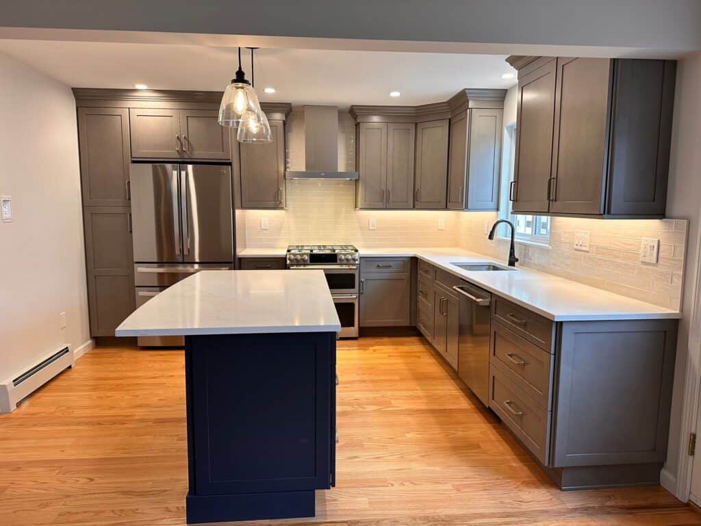 Contemporary kitchen with gray cabinets, white countertops, and stainless steel appliances.