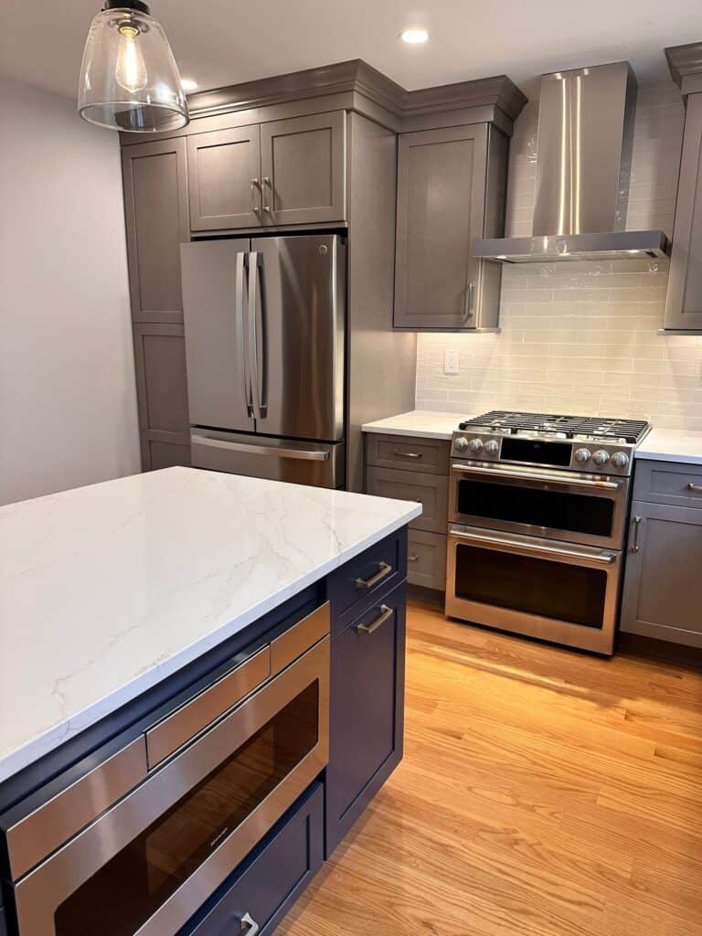 Contemporary kitchen with gray cabinets, stainless steel appliances, and a white marble island.