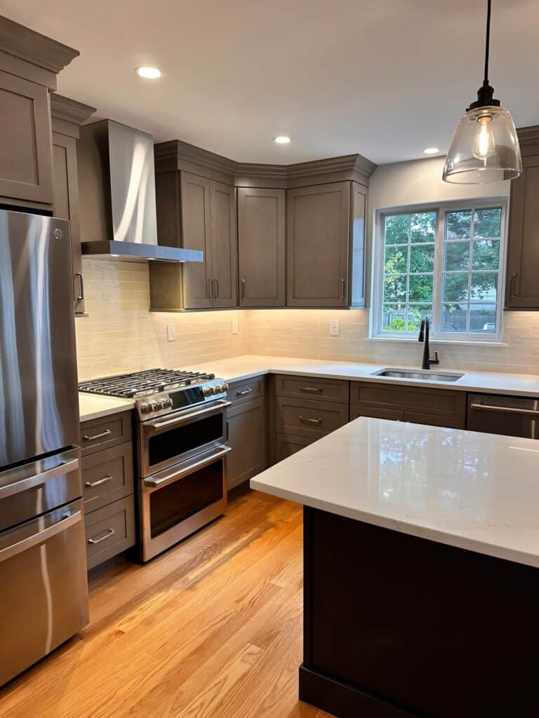 Contemporary gray kitchen with stainless steel appliances and large window.