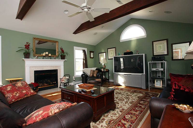 Spacious living room with green walls, fireplace, and modern entertainment setup.
