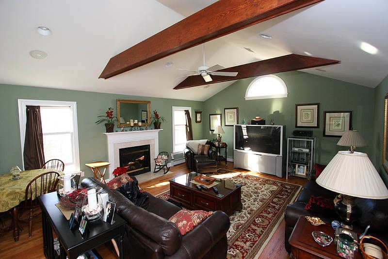 Spacious living room with green walls, fireplace, and modern entertainment center.