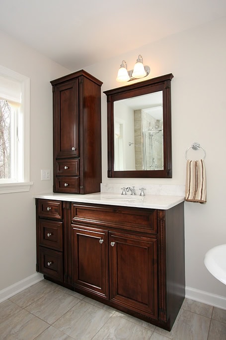Bathroom vanity with dark wood cabinetry and mirror.