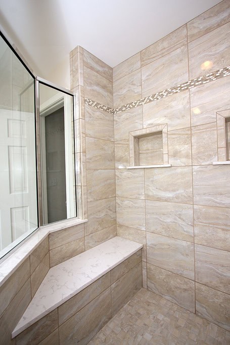 Elegant bathroom shower with beige marble tiles and built-in niches for toiletries.