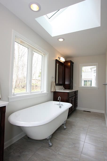 Elegant bathroom featuring a vintage clawfoot bathtub, large windows, and a skylight for natural lig.